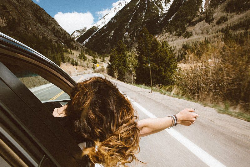 Young woman leans out car window to feel the fresh mountain air. Original public domain image from Wikimedia Commons